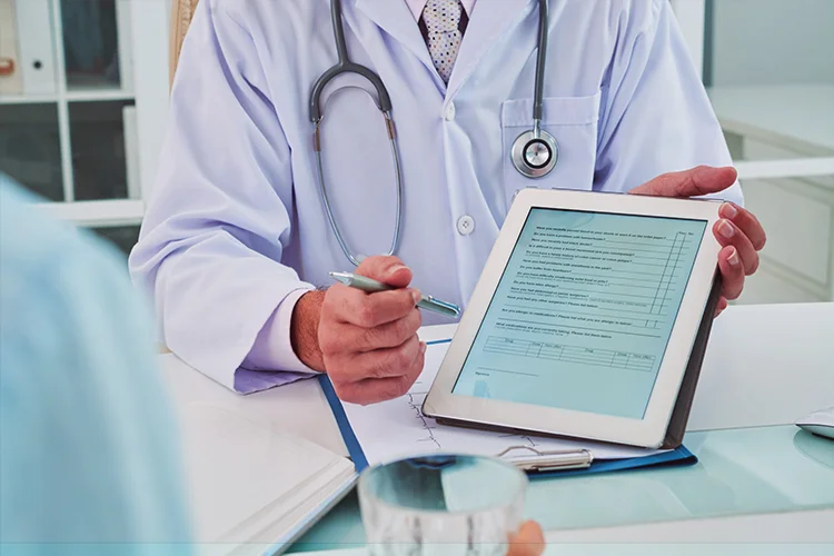 Doctor showing patient records on tablet, representing ease of recording and retrieving cases with the best clinic management software.