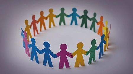 Colorful paper figures holding hands in a circle, symbolizing unity and teamwork in social cause projects that help communities.